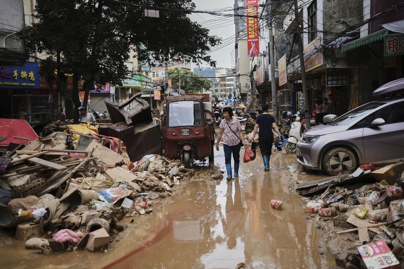ARCHIVO - En esta imagen, distribuida por la agencia noticiosa estatal Xinhua, residentes cruzan una calle anegada llena de escombros tras el desbordamiento de un río después de días de intensas precipitaciones, en el condado de Huaiji, en la provincia de Guangdong, en el sur de China, el 19 de junio de 2025. (Deng Hua/Xinhua vía AP, archivo)