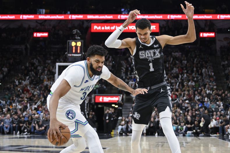 El dominicano Karl-Anthony Towns, de los Timberwolves disputa ante Victor Wembanyama (1), durante la segunda mitad del juego de la NBA, el sábado 27 de enero, de 2024. (AP Foto/Darren Abate)