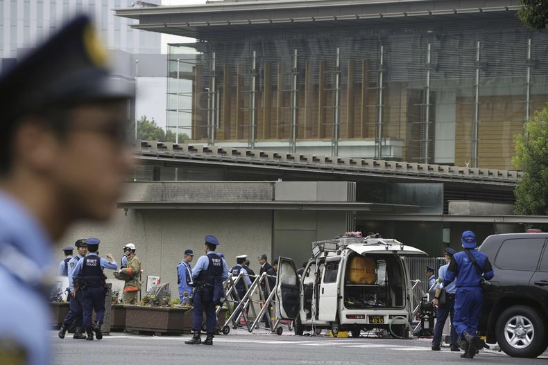 Agentes de policía trabajan cerca de un vehículo (centro) que fue estrellado contra una barricada cerca de la oficina del primer ministro (detrás), en Tokio, el 19 de octubre de 2024. (Kyodo News vía AP)