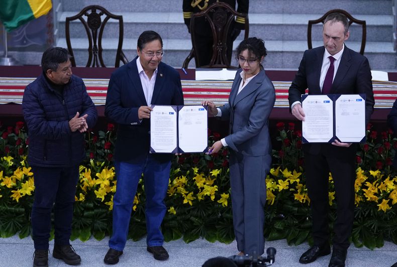 El presidente de Bolivia, Luis Arce, segundo desde la izquierda, su vicepresidente David Choquehuanca, extremo izquierda, y Karla Calderón, presidenta de la empresa estatal boliviana Yacimientos de Litio Bolivianos, tercera desde la izquierda, presentan su documento de acuerdo firmado junto a Yuri Alexanderovich. Ulyanin, representante de Uranium One Group, una filial de la rusa Rosatom, sosteniendo su copia durante una ceremonia en el palacio de gobierno en La Paz, Bolivia, el miércoles 13 de diciembre de 2023. (AP Foto/Juan Karita)