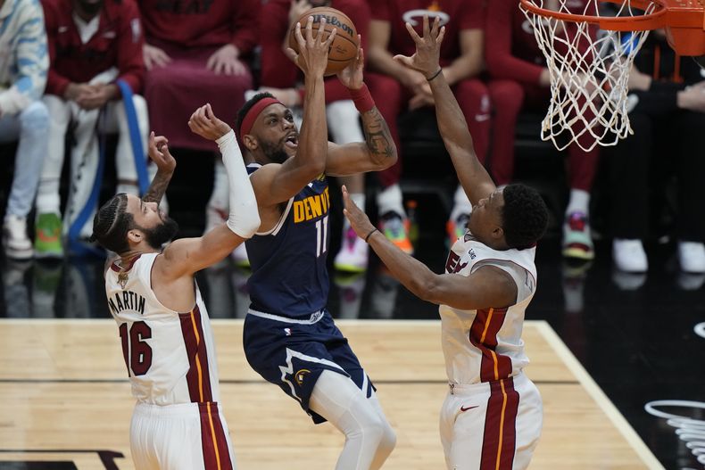 El alero de los Nuggets de Denver Bruce Brown avanza hacia la canasta mientras lo defienden el alero Caleb Martin y el base Kyle Lowry del Heat de Miami en el juego 4 de las Finales de la NBA el viernes 9 de junio del 2023. (AP Foto/Lynne Sladky)