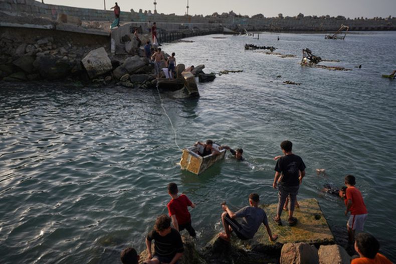 Jóvenes palestinos juegan y nadan en una cuenca portuaria en Ciudad de Gaza, el 19 de abril de 2026. (Foto AP/Jehad Alshrafi)