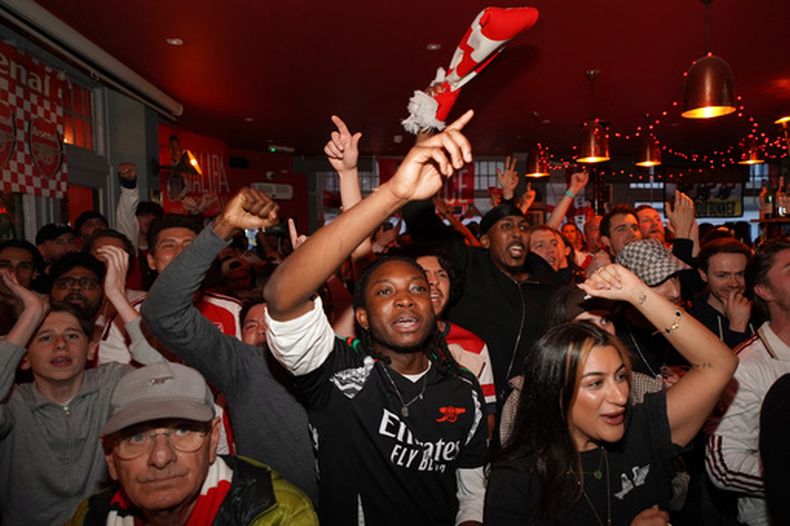 Hinchas de Arsenal celebran mientras observan desde un pub el partido entre Bournemouth y Manchester City por la Liga Premier inglesa, el martes 19 de mayo de 2026, en Londres. (AP Foto/Alberto Pezzali)
