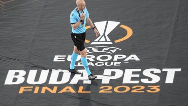El árbitro británico Anthony Taylor camina sobre una manta luego de dirigir la final de la Liga Europa entre Sevilla y Roa, el miércoles 31 de mayo de 2023, en Budapest (AP Foto/Darko Vojinovic)
