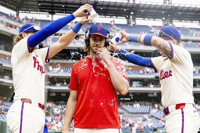 El lanzador abridor de los Filis de Filadelfia, Aaron Nola, es rociado con agua por Alec Bohm, izquierda, y Bryson Stott después de que su equipo derrotó a los Cerveceros de Milwaukee en un juego de béisbol, el miércoles 5 de junio de 2024, en Filadelfia. (AP Foto/Laurence Kesterson)