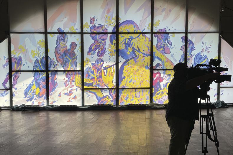 Un hombre de pie junto a una obra de arte de la artista ucraniana Julia Tveritina para crear conciencia sobre las víctimas de abuso sexual, en el centro de arte de Kiev, Ucrania, el miércoles 19 de junio de 2024. (AP Foto/Derek Gatopoulos)