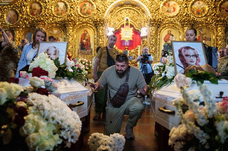Un hombre al lado de los ataúdes de niñas muertas en un ataque ruso, en Kiev, Ucrania, el 19 de mayo del 2026. (AP foto/Evgeniy Maloletka)