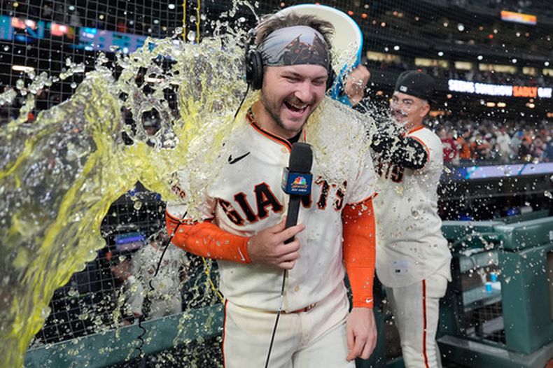 Patrick Bailey, de los Gigantes de San Francisco, recibe un baño por parte de Willy Adames, derecha, después de batear el jonrón decisivo de tres carreras contra los Dodgers de Los Ángeles en la séptima entrada del juego de béisbol de Grandes Ligas, el miércoles 22 de abril de 2026, en San Francisco. (AP Foto/Tony Avelar)