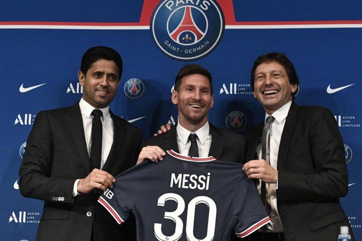 El presidente de Qatar del Paris Saint-Germain, Nasser Al-Khelaifi (L), y el Director Deportivo del Paris Saint-Germain, Leonardo Nascimento de Araujo (R), junto a Messi que sostiene su camiseta número 30 . (Télam)STEPHANE DE SAKUTIN | AFP