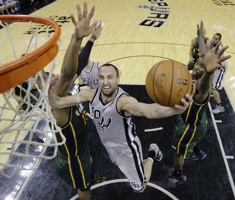 El argentino Manu Gin&oacute;bili, de los Spurs de San Antonio, dispara delante de Derrick Favors, del Jazz de Utah, en el encuentro del domingo 16 de marzo de 2014 (AP Foto/Eric Gay)