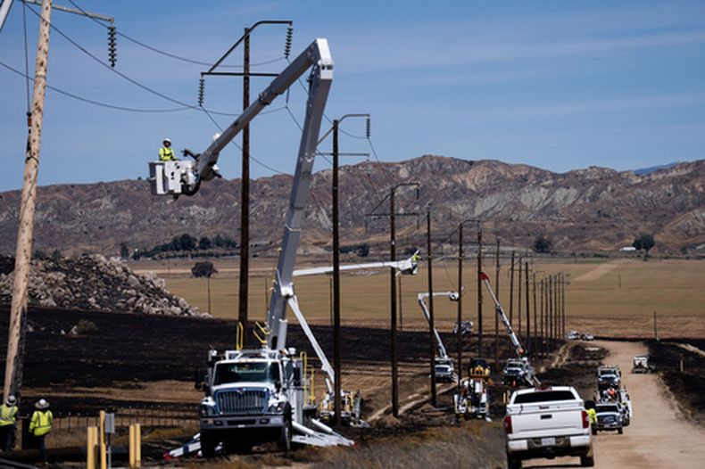 Cuadrillas de la compañía eléctrica trabajan para restablecer el suministro eléctrico en una zona afectada por el incendio Springs en Moreno Valley, California, el sábado 4 de abril de 2026. (Foto AP/Jae C. Hong)