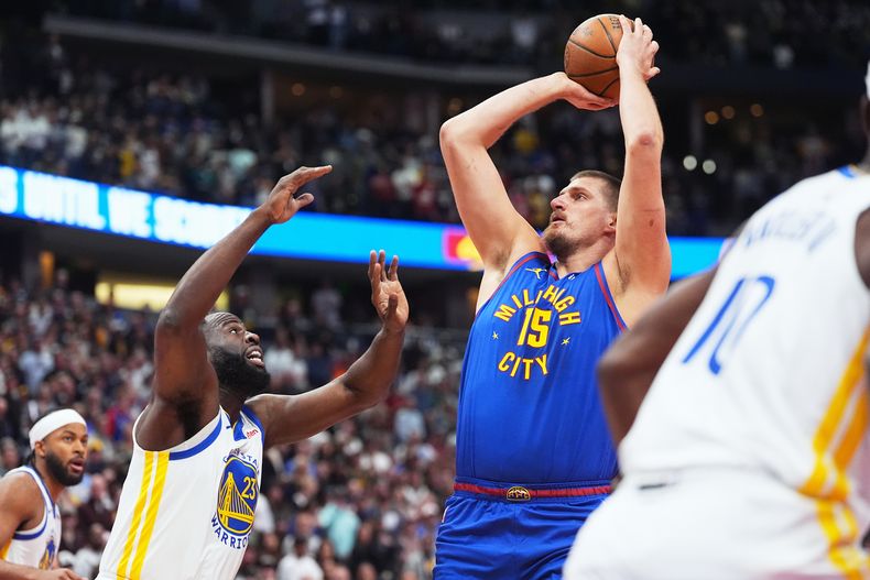 El serbio Nikola Jokic, de los Nuggets de Denver, busca disparar frente a Draymond Green, de los Warriors de Golden State, en el partido del viernes 7 de noviembre de 2025 (AP Foto/David Zalubowski)