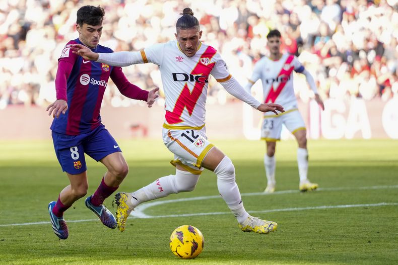Alfonso Espino del Rayo Vallecano pelea por el balón con Pedri del Barcelona en el encuentro de la liga española el sábado 25 de noviembre del 2023. (AP Foto/Jose Breton)