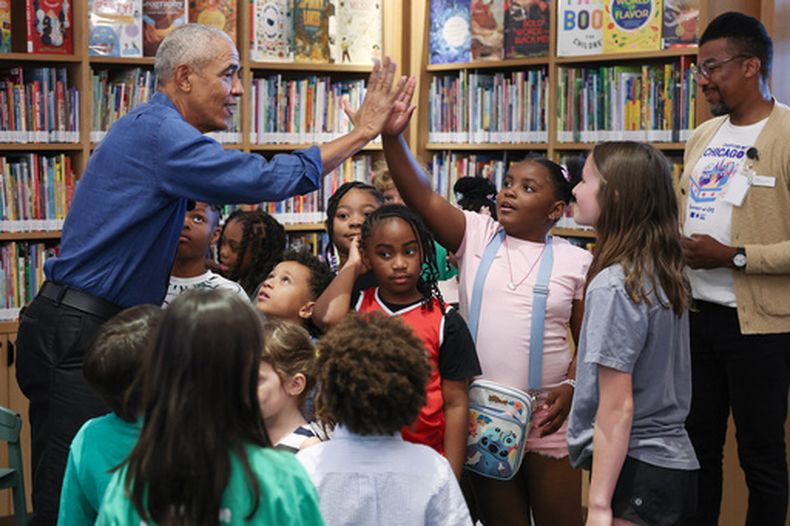 El expresidente Barack Obama choca palmas durante una lectura de libros con niños, el día de la inauguración del Centro Presidencial Barack Obama en John Lewis Plaza, el viernes 19 de junio de 2026, en Chicago. (Win McNamee/Pool Foto vía AP)