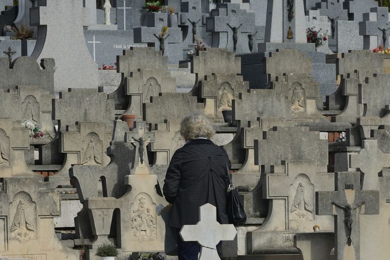 Una mujer de pie frente a una tumba en el cementerio de Almudena, en el Día de Todos los Santos, una festividad católica para reflexionar sobre los santos y los familiares difuntos, en Madrid, España, el viernes 1 de noviembre de 2024. (AP Foto/Paul White)