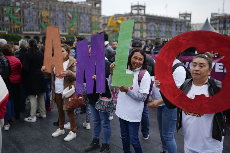 Simpatizantes del presidente mexicano Andrés Manuel López Obrador sostienen sus iniciales frente al Palacio Nacional donde realiza su última conferencia de prensa matutina en la Ciudad de México, el lunes 30 de septiembre de 2024. (AP Foto/Eduardo Verdugo)