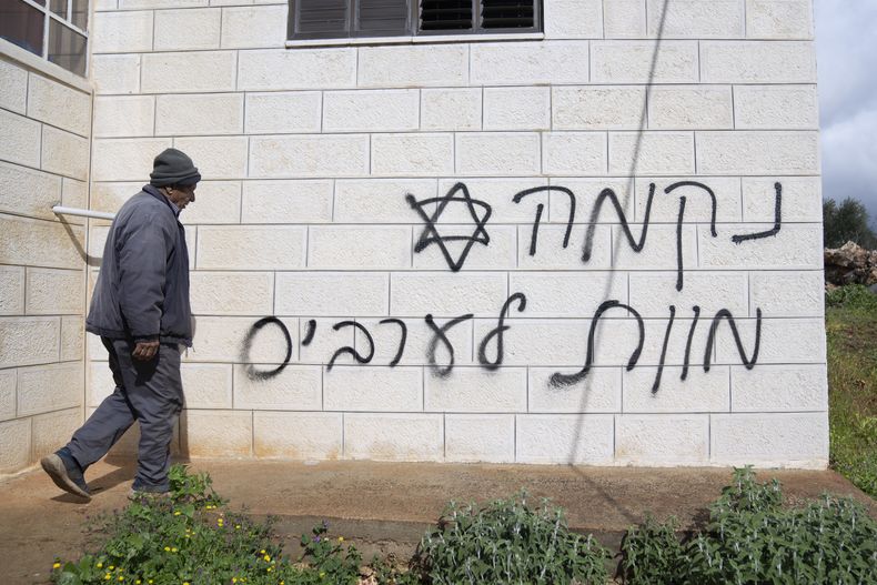 Un hombre pasa frente a una pared con un graffiti que dice en hebreo venganza, muerte a los árabes, supuestamente pintado por colonos judíos en la aldea palestina de Turmus Ayya, en Cisjordania, el 18 de febrero de 2024. (Foto AP/Nasser Nasser, Archivo)
