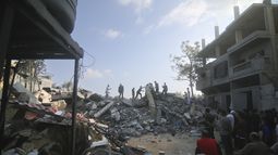 Un grupo de palestinos revisan los escombros de un edificio destruido por un ataque aéreo israelí en Rafah, en la Franja de Gaza, el sábado 14 de octubre de 2023. (AP Foto/Hatem Ali)