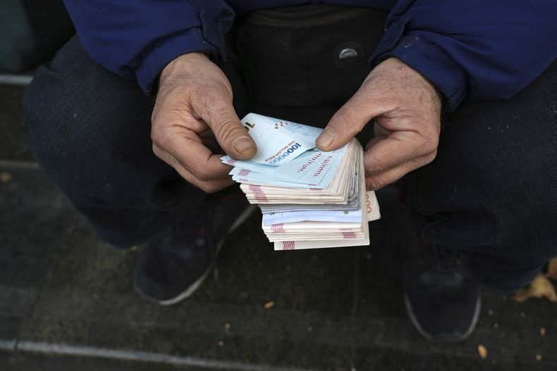 ARCHIVO - Un cambista callejero posa para una foto sin mostrar su rostro mientras cuenta billetes en un distrito comercial en el centro de Teherán, Irán, el 23 de diciembre de 2022. (AP Foto/Vahid Salemi, archivo)