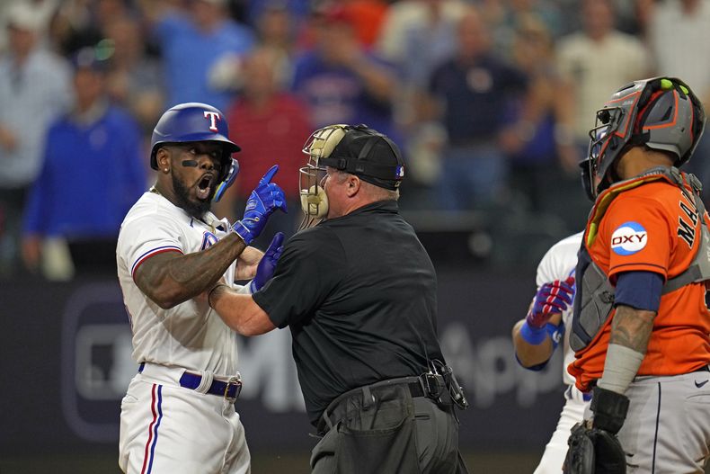 El umpire Marvin Hudson trata de detener al cubano Adolis García, de los Rangers de Texas, quien increpa al cátcher boricua Martín Maldonado, de los Astros de Houston, tras recibir un pelotazo en el quinto juego de la Serie de Campeonato de la Liga Americana, el viernes 20 de octubre de 2023 (AP Foto/Julio Cortez)