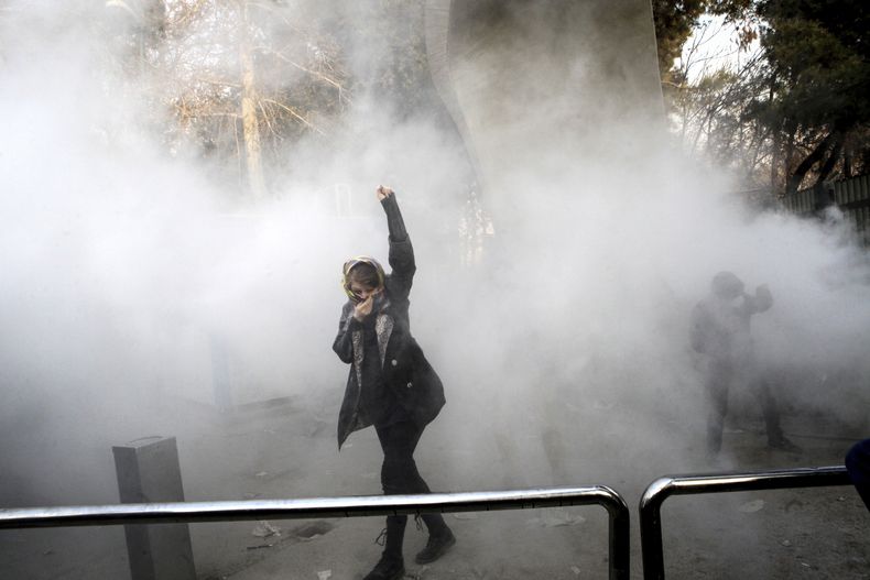 ARCHIVO – En esta foto, tomada por una persona no empleada por The Associated Press y obtenida por la AP fuera de Irán, un estudiante universitario asiste a una protesta en la Universidad de Teherán después de que la policía antidisturbios arrojara una granada de humo en Teherán, Irak, el 30 de diciembre de 2017, AP foto, Archivo)