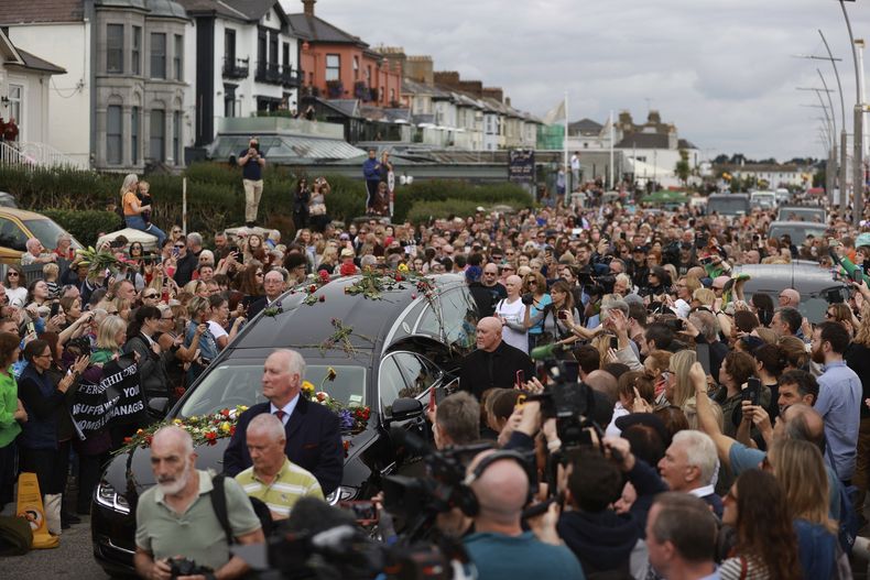 Fans de Sinead OConnor rodean su cortejo fúnebre en Bray, la ciudad natal de la cantante el condado de Wicklow, Irlanda, el martes 8 de agosto de 2023. La familia de OConnor invitó al público al paseo marítimo de Bray para despedirse de la artista. (Liam McBurney/ PA vía AP)