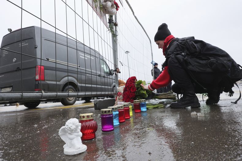 Una mujer deposita flores junto a la cerca del Crocus City Hall, una sala de conciertos de Moscú, Rusia, el 23 de marzo de 2024, un día después de un ataque que dejó varias docenas de muertos. (AP Foto/Vitaly Smolnikov)