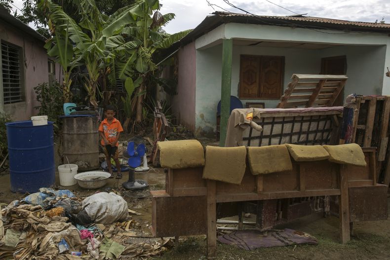 Un niño se encuentra junto a un colchón y otras pertenencias en la calle una semana después de que el huracán Oscar azotara la ciudad de Imías en la provincia de Guantánamo, Cuba, el martes 29 de octubre de 2024. (AP Foto/Ariel Ley, Pool)