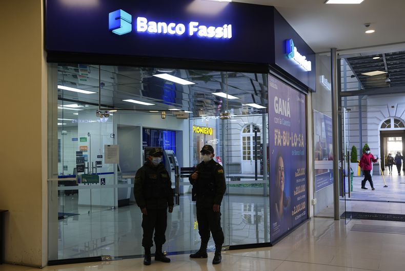 La policía hace guardia afuera de una sucursal cerrada del Banco Fassil donde cuelga un mensaje para sus clientes en La Paz, Bolivia, el miércoles 26 de abril de 2023. (AP Foto/Juan Karita)