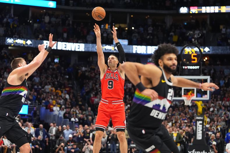Nikola Vučević (9), de los Bulls de Chicago, lanza un triple mientras Nikola Jokić, izquierda, de los Nuggets de Denver, llega tarde a la marcación defensiva, y Jamal Murray, derecha, defiende en la segunda mitad del juego de baloncesto de la NBA, el lunes 17 de noviembre de 2025, en Denver. (AP Foto/David Zalubowski)