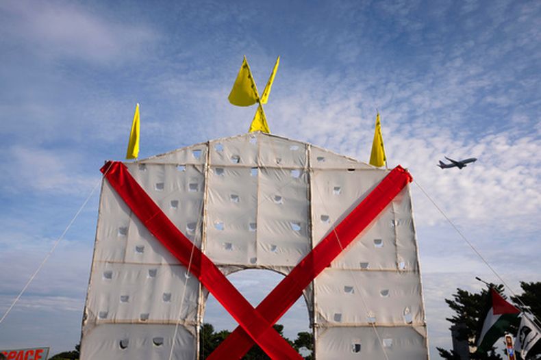 Un avión sobrevuela una estructura en forma de arco que levantaron los manifestantes en el Memorial Circle, en Arlington, Virginia, para protestar contra el proyecto del Arco del Triunfo, el jueves 1 de octubre de 2026. (AP Foto/Allison Robbert)