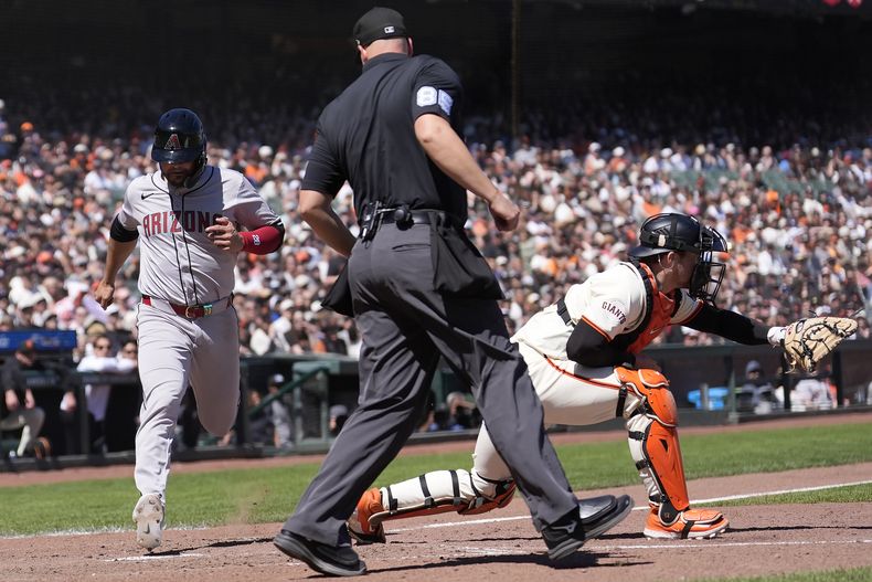 El umpire Stu Scheurwater, centro, observa anotar carrera a Eugenio Suárez, izquierda, de los Diamondbacks de Arizona, mientras el receptor Patrick Bailey, de los Gigantes de San Francisco, espera por la pelota, durante la sexta entrada del juego de béisbol del domingo 21 de abril de 2024, en San Francisco. (AP Foto/Jeff Chiu)