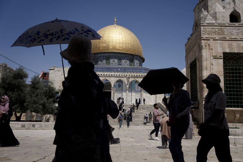 Turistas se protegen del sol a mediodía en el complejo de la mezquita de Al-Aqsa, en la Ciudad Vieja de Jerusalén, el 26 de julio de 2023. (AP Foto/Maya Alleruzzo)