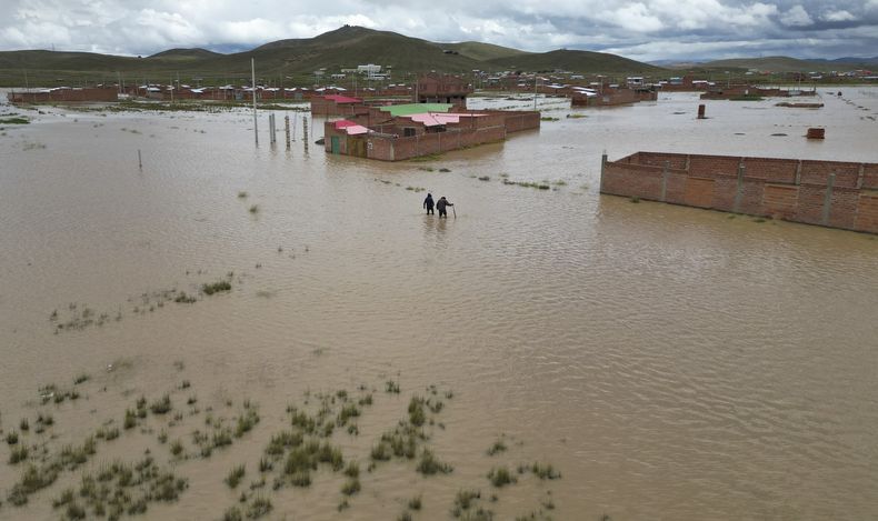 Residentes recorren calles inundadas tras el desbordamiento del río Pallina en Viacha, Bolivia, el miércoles 12 de marzo de 2025. (Foto AP/Juan Karita)