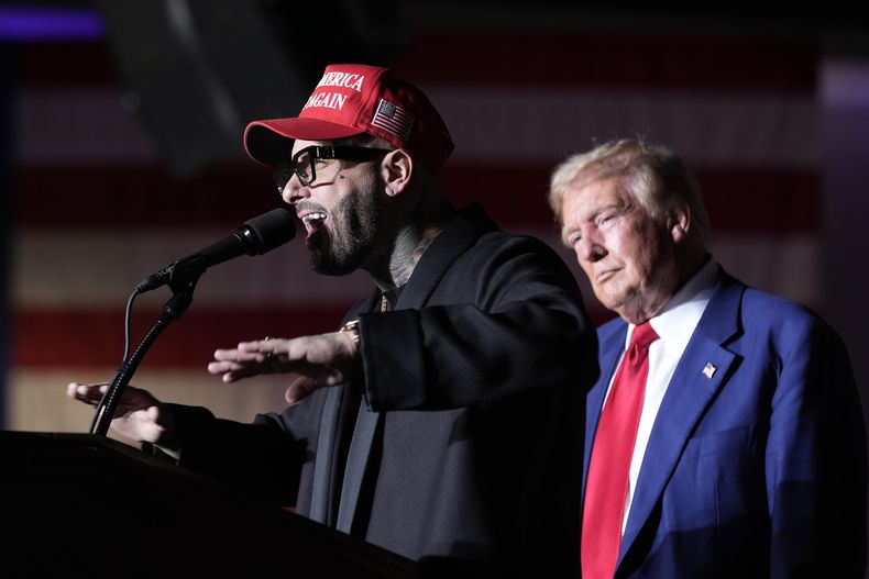 Nicky Jam habla mientras el expresidente Donald Trump, candidato presidencial republicano, escucha durante un evento de campaña en el World Market Center, el viernes 13 de septiembre de 2024, en Las Vegas. (Foto AP/Alex Brandon)