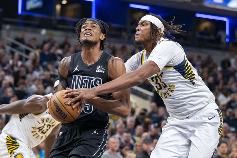 El pívot de los Pacers de Indiana, Myles Turner (33), intenta detener un tiro del pívot de los Nets de Brooklyn, Nic Claxton (33), durante la primera mitad de un partido de baloncesto de la NBA en Indianápolis, el sábado 22 de marzo de 2025. (AP Foto/Doug McSchooler)