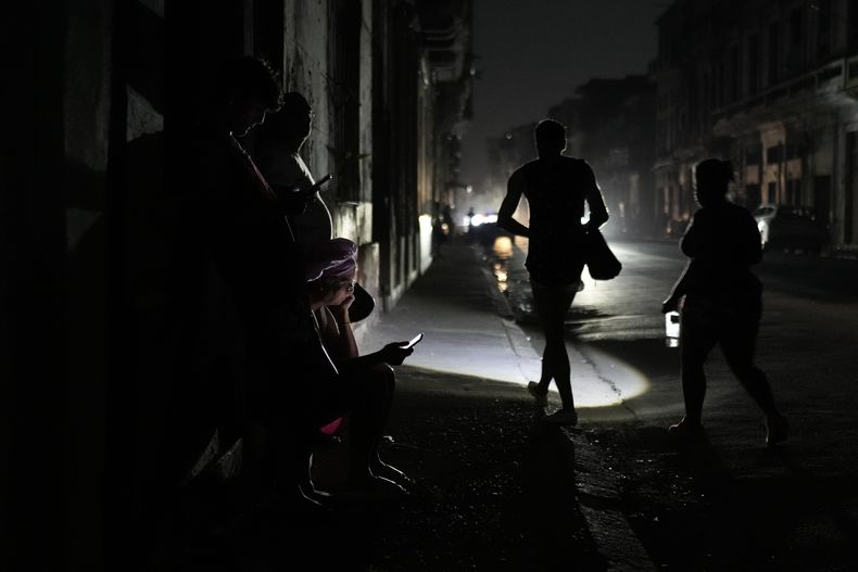 Algunas personas caminan por la calle durante un apagón general el viernes 14 de marzo de 2025, en La Habana, Cuba. (AP Foto/Ramón Espinosa)
