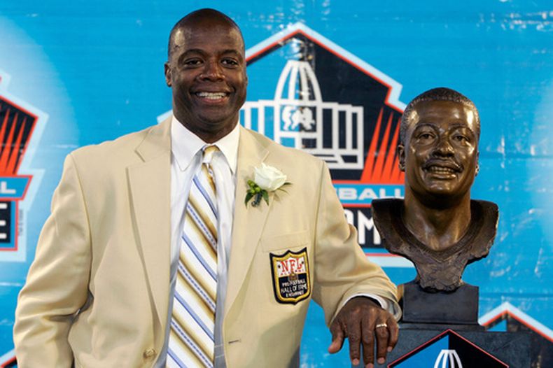 ARCHIVO - Darrell Green, exjugador de los Redskins de Washington, está parado a un costado de su busto de bronce del Salón de la Fama de Fútbol Americano, en Canton, Ohio, el 2 de agosto de 2008. (AP Foto/Kiichiro Sato, Archivo)