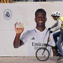Un ciclista pasa frente a un afiche de Vinicius Junior, el delantero brasileño del Real Madrid, frente al estadio Santiago Bernábeu, el lunes 22 de mayo de 2023 en Madrid. (AP Foto/Paul White)