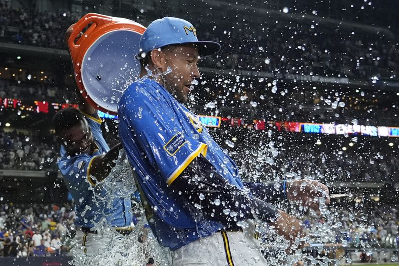 El venezolano Andruw Monasterio, de los Cerveceros de Milwaukee, vacía la hielera encima de Blake Perkins, quien definió el duelo del viernes 8 de agosto de 2025 ante los Mets de Nueva York (AP Foto/Aaron Gash)