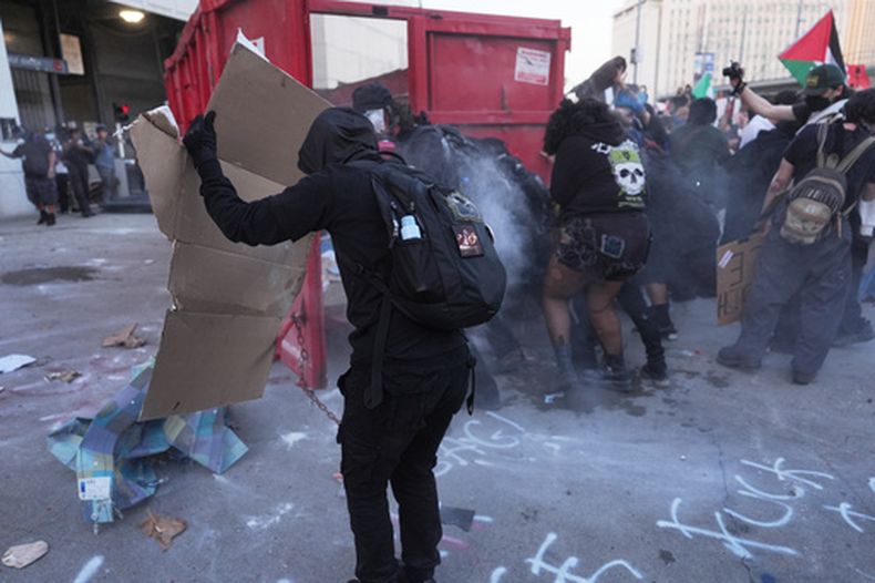 Manifestantes se protegen del gas lacrimógeno durante los enfrentamientos con la policía federal en el Centro Metropolitano de Detención, en el centro de Los Ángeles, el viernes 30 de enero de 2026. (AP Foto/Jae C. Hong)