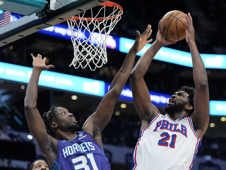 Joel Embiid, pívot de los 76ers de Filadelfia, dispara frente a Nathan Mensah, de los Hornets de Charlotte, en el encuentro del sábado 20 de enero de 2024 (AP Foto/Chris Carlson)