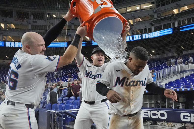 Primera base de los Marlins de Miami Jake Burger y el bateador designado Jonah Bride bañan al campocorto Xavier Edwards tras su sencillo remolcador de la victoria en la décima ante los Nacionales de Washington el miércoles 4 de septiembre del 2024. (AP Foto/Wilfredo Lee)