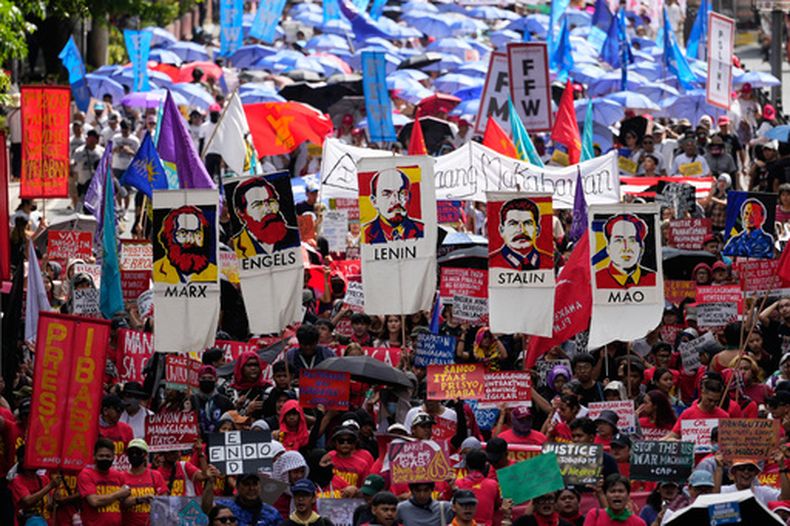Manifestantes sostienen carteles con la imagen de líderes comunistas durante una marcha hacia el palacio presidencial de Malacanang con motivo del Primero de Mayo, en Manila, Filipinas, el 1 de mayo de 2026. (AP Foto/Aaron Favila)