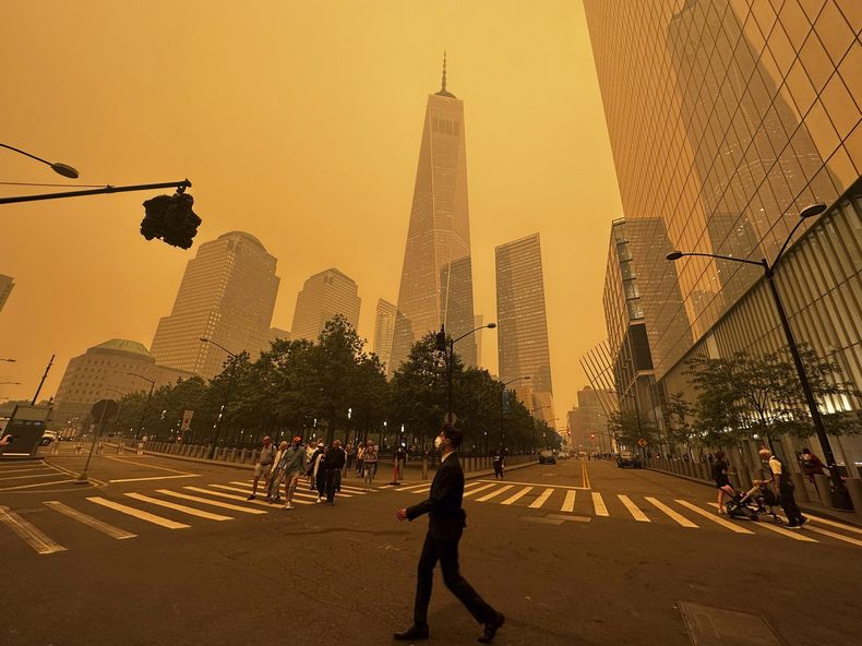 Peatones pasan junto al One World Trade Center (centro), en medio de la humareda causada por los incendios forestales en Canadá, el 7 de junio de 2023, en la Ciudad de Nueva York. (AP Foto/Julie Jacobson)
