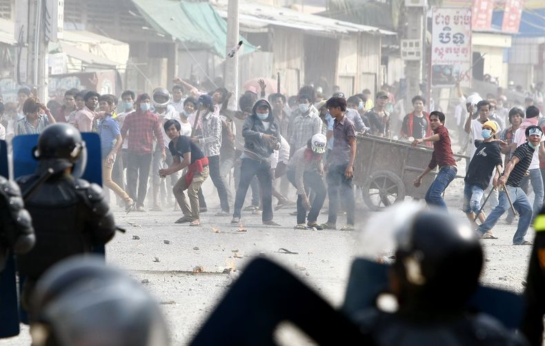 Trabajadores de la confecci&oacute;n arrojan objetos contra polic&iacute;as antidisturbios durante un paro de labores cerca de una f&aacute;brica de Canadia Center, en el complejo Stung Meanchey en las afueras de Phnom Penh, Camboya, el viernes 3 de enero