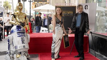 Billie Lourd, izquierda, hija de la fallecida actriz Carrie Fisher y Mark Hamill posan con la estrella de Fisher en el Paseo de la Fama de Hollywood junto a los personajes de Star Wars C-3PO y R2-D2 durante una ceremonia póstuma en Los Ángeles el jueves 4 de mayo de 2023. La fecha se conoce también como Día de Star Wars, en homenaje a las películas de Star Wars en las que Fisher interpretó a la Princesa Leia. (Foto AP/Chris Pizzello)