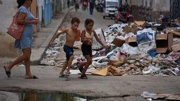 Niños corren junto a un montón de basura acumulada en una calle durante un apagón en La Habana, Cuba, el lunes 6 de julio de 2026. (Foto AP/Ramón Espinosa)