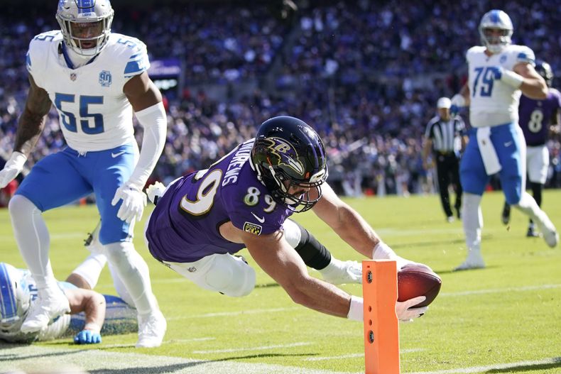 Mark Andrews (89), tight end de los Ravens de Baltimore, estira las manos con el ovoide para conseguir un touchdown ante la mirada del linebacker Derrick Barnes (55), de los Lions de Detroit, durante la primera mitad del partido de la NFL, del domingo 22 de octubre de 2023, en Baltimore. (AP Foto/Alex Brandon)