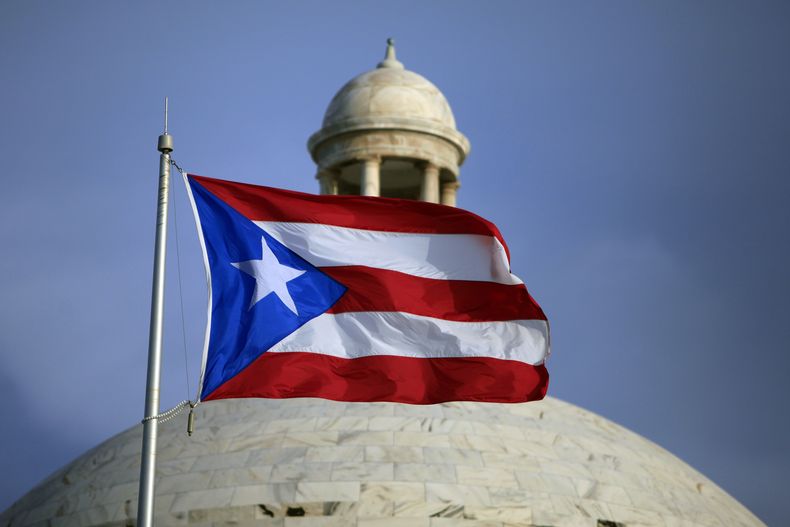 ARCHIVO - La bandera de Puerto Rico ondea frente al edificio del Capitolio en San Juan, Puerto Rico, 29 de julio de 2015. (AP Foto/Ricardo Arduengo, Archivo)